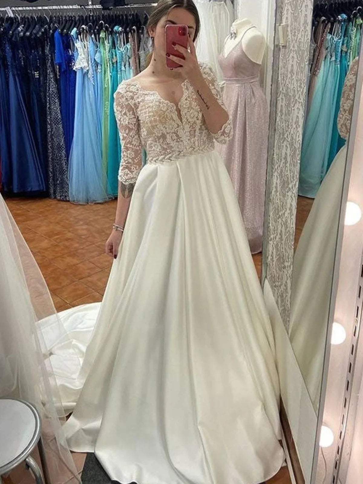 Vestido de novia largo de satén con escote en forma de A y mangas color marfil.