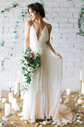 Sencillo vestido de novia color marfil con escote pronunciado en V, cola y tirantes